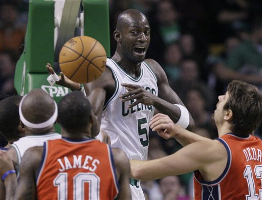 Boston Celtics forward Kevin Garnett (5) dishes the ball from under the basket as New Jersey Nets forward Damion James (10) and center Mehmet Okur (13), of Turkey, defend in the first half Wednesday in Boston.
