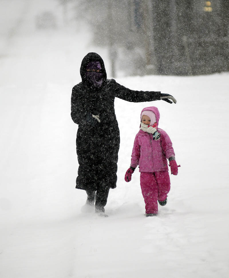 WHITE OUT: Maureen Drouin and her daughter, Lily Drouin-Scease, 4, descend Central Street in Hallowell Thursday. The couple were exploring the snow storm near their home at lunch.