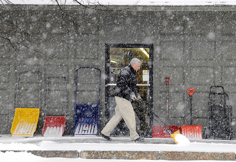 INVENTORY: Bill Harvey moves the snow Thursday that piled up in front of his Gardiner business, Harvey's Hardware. Several inches of snow of fell across Maine.
