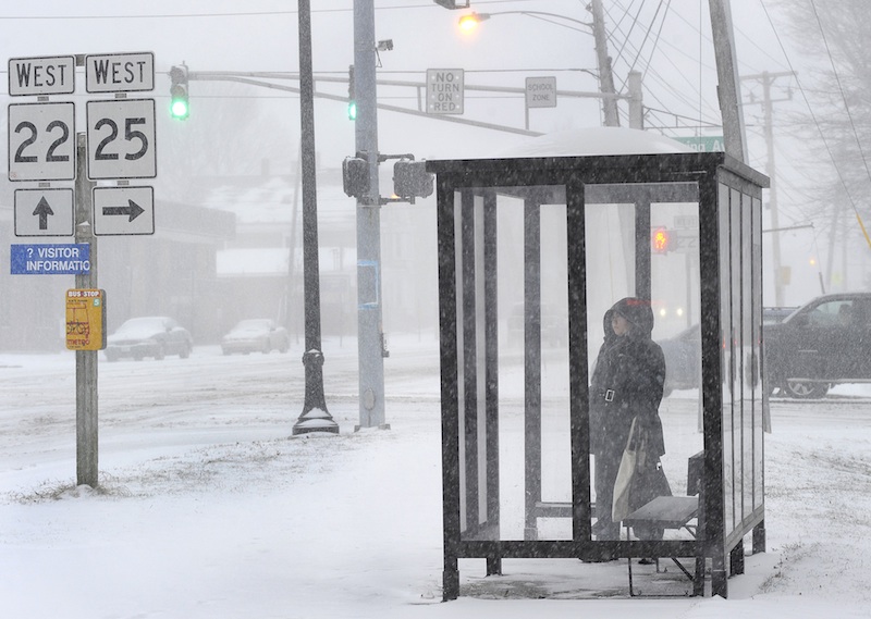Sarah Melanson from Portland waits for a bus in a shelter along Park Ave on Thursday morning while trying to get to work. Commuters were finding the going slow as Maine receives its first snowstorm of the new year.