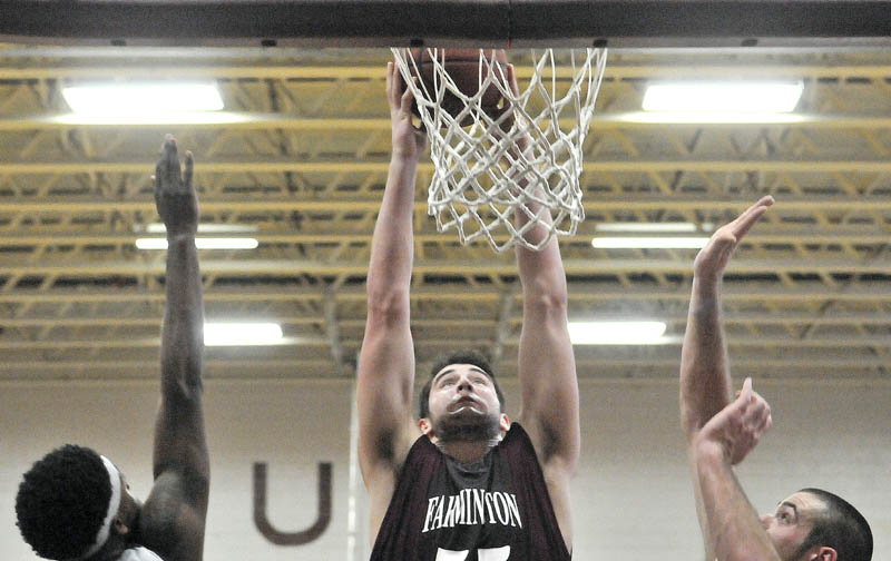 TAKE THAT: University of Maine at Farmington’s Ben Johnson, center, dunks an offensive rebound over Lyndon State College defenders John Williams, left, and Jason Gray, right, in the first half Saturday at Dearborn Gymnasium at University of Maine at Farmington.