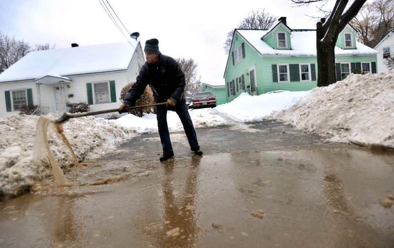 MESSY: Brian Bonsall clears a collecting reservoir of ice water at the mouth of his driveway on North Street in Waterville Friday.