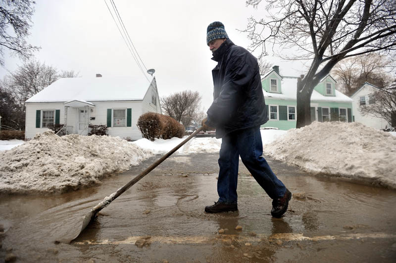 CLEARING THE WAY: Brian Bonsall clears a collecting reservior of ice water at the mouth of his driveway on North Street in Waterville on Friday.
