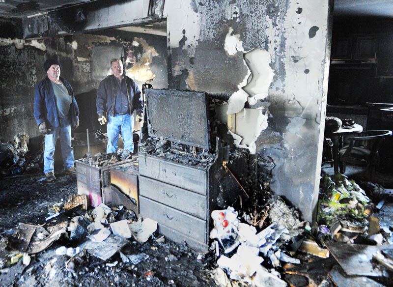 Rodney Vigue, left, and Mike Burton survey the damage from an overnight fire in Vigue’s Augusta home on Friday morning. “It’s a mess,” Vigue said. “The whole thing is totaled.” Vigue, 51, shares the home with his grown children and a 5-year-old grandchild. See story on B1.