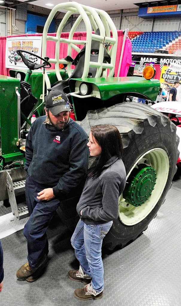BIG TRACTOR: Phil Bisson, left, stands next to his 9,300-pound class pulling tractor and chats with Outlaw class driver Rachel Dubois during the opening night of the Northeast Motorsports Expo on Friday evening at the Augusta Civic Center.