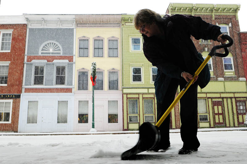 Ann Ebert shovels snow in front of Lisa's Legit Burritos during the first snow storm of the year on Thursday morning in downtown Gardiner.