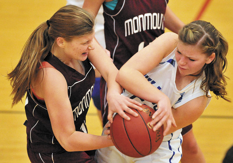 Monmouth Academy’s Amanda Anair, left, and Madison Memorial High School’s Kirsten Wood, right, battle for the ball in the second quarter Thursday night in Madison. The Bulldogs won 49-30.