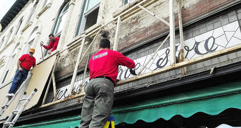 This May 2011 file photo shows Richard Parkhurst, left, and Tobias Parkhurst, of Oakes and Parkhurst Glass, removing the vinyl and metal facade that covered the stained glass window that Glenn Parkhurst, of Stained Glass Express, is cleaning off on Water Street in downtown Augusta. The window says Hersey's Show Store in blue script. The building is owned by Tobias Parkhurst and is home of the Downtown Diner.