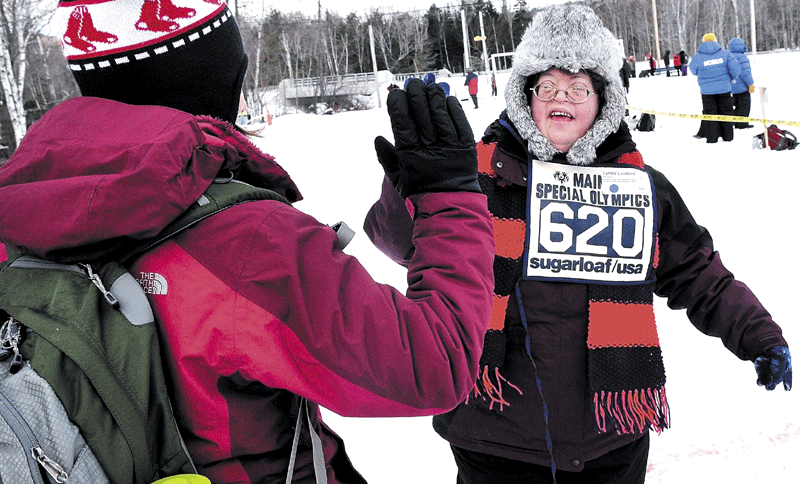 ABOVE: Athlete Lynda Lambert makes it over the finish line in the snowshoe competition as Unity College student volunteer Rebecca Fisher congratulates her.