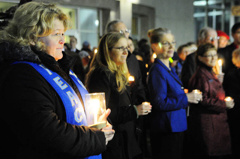 The Rev. Carie Johnsen, the minister of Unitarian Universalist Community Church of Augusta, far left, holds a candle at a vigil outside the State House before Gov. Paul LePage's first State of the State address on Tuesday night in Augusta.