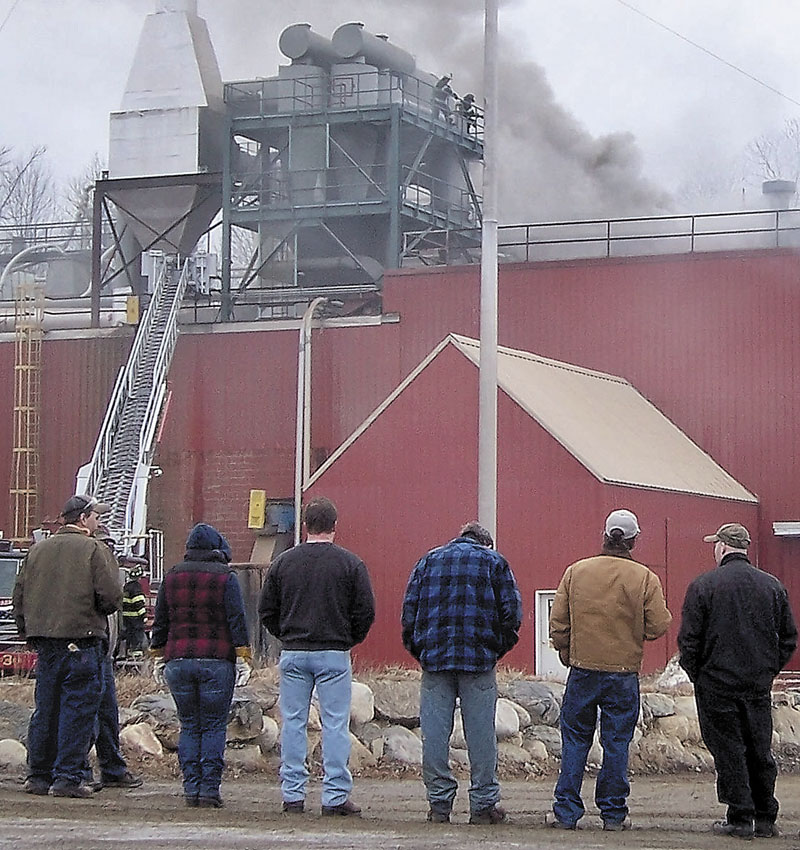 FIRE IN STRONG: Workers watch as smoke billows from the Geneva Wood Fuels plant on Thursday morning. A fire started on the third floor about 8 a.m. and the wood pellet mill, where 21 people work, is expected to reopen in the next few days, company officials said.