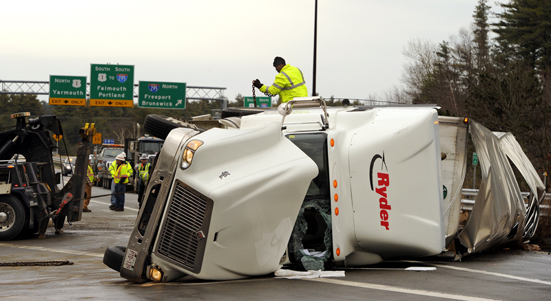 Workers from Stewart's Trucking and Heavy Hauling work on righting a flipped tractor-trailer on the Falmouth spur near the I-295 ramp today. The accident temporarily closed Exit 11 and access to the turnpike.