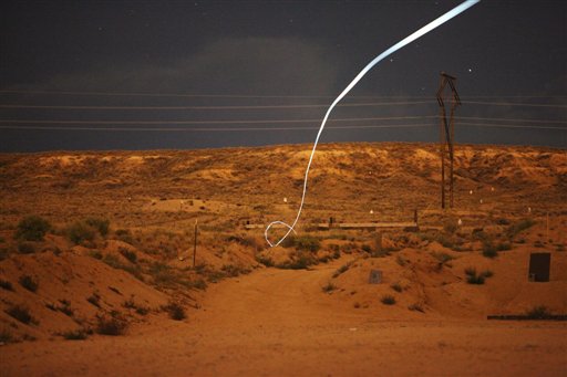 In this undated time-exposure provided by Sandia National Laboratories, a light-emitting diode attached to a self-guided bullet shows the bullet's path toward its target during a nighttime field test.