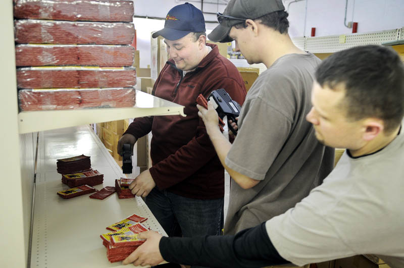 Nick Hamel, right, Selby Landmann, center, and Scott Boucher price firecrackers recently at Pyro City Fireworks on Route 202 in Manchester. Employees stocked up for the Thursday opening of the first fireworks store in Maine since the ban on fireworks was lifted last year.