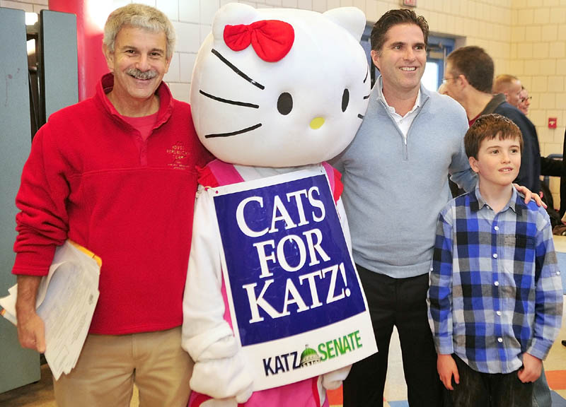 State Senator Roger Katz, left, a costumed campaigner, Tagg Romney and his son Joe pose for a photo before the Kennebec County Super Caucus at Farrington School in Augusta on Saturday.