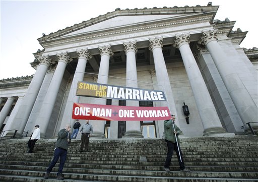 In ths Jan. 23, 2012, photo, Ken Jackson, right, and Don Taylor carry a sign that reads "Stand Up For Marriage – One Man + One Woman" following a rally at the Capitol in Olympia, Wash.