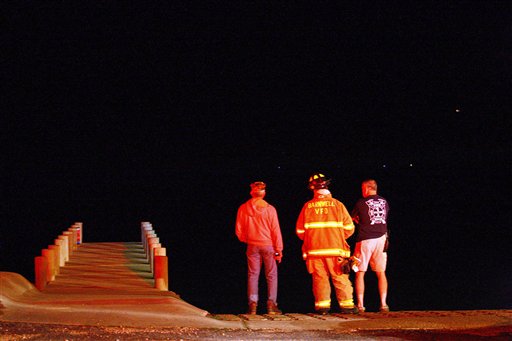 Firefighters from the Barnwell Volunteer Fire Department look out into Mobile Bay as they wait on standby in Point Clear, Ala. after a U.S. Coast Guard helicopter crashed in the bay late Tuesday.