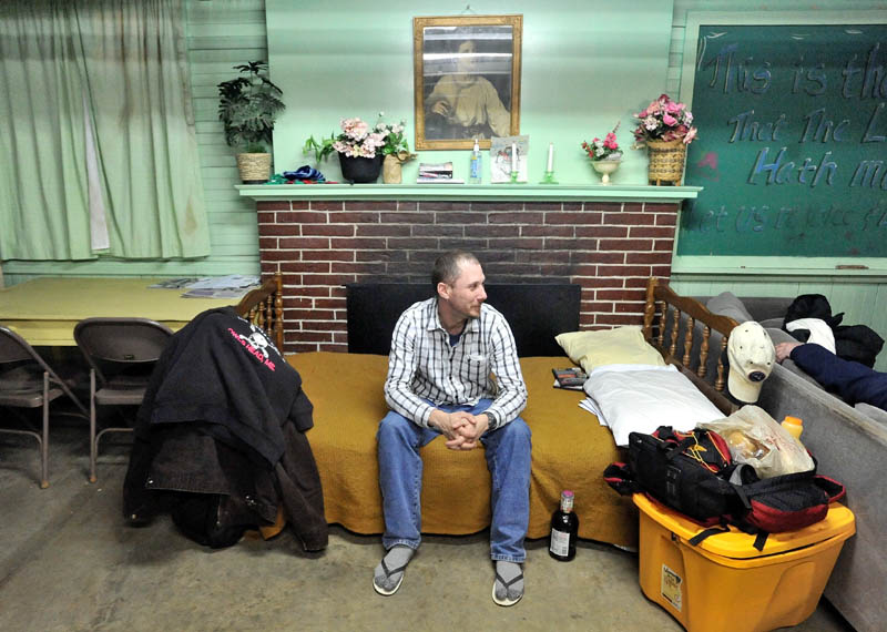 A WARM PLACE TO SLEEP: Corey Conway sits on his bed at the overflow homeless shelter in Waterville on Monday night.