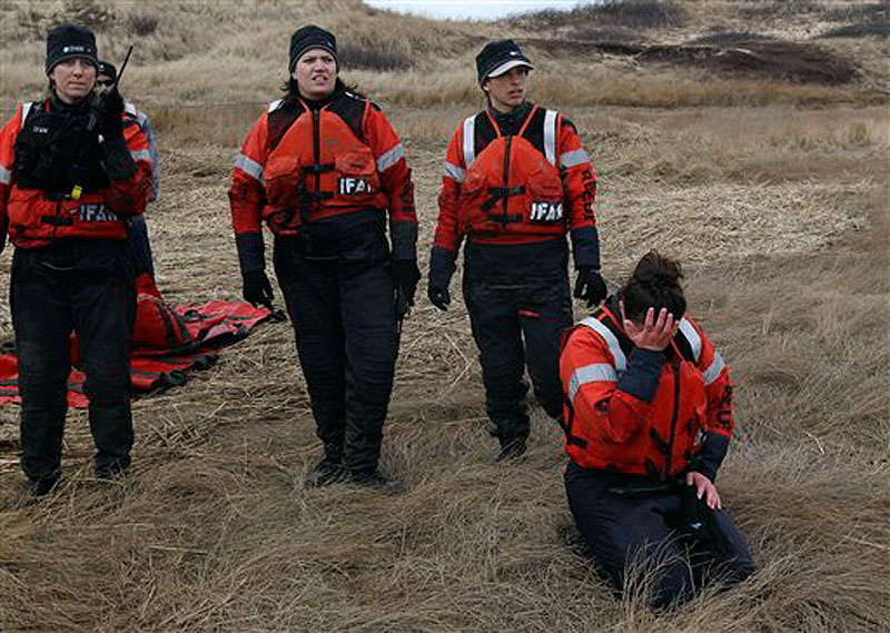 Linda D'eri places her head in her hand as Katie Moore, Misty Niemeyer and Kat Rose (left to right) watch a group of dolphins they rescued move away from the mud flat they were stranded on during low tide in Wellfleet, Mass., on Tuesday, Feb. 14, 2012. Ten of the dolphins were saved and one perished during the event. (AP Photo/Stephan Savoia)