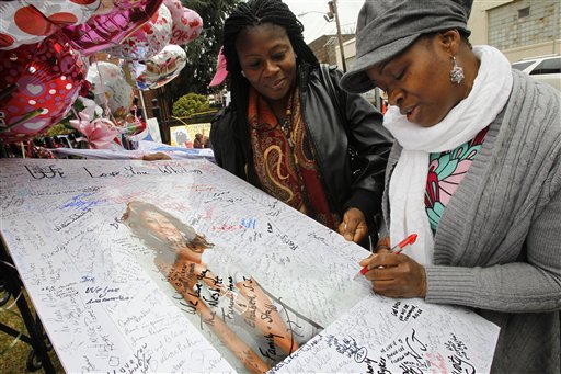 Yamda Johnson watches as her friend Regina Kujemya, both from Staten Island, N.Y. signs a poster of Whitney Houston while paying their respects at New Hope Baptist Church, in Newark, N.J., on Wednesday.
