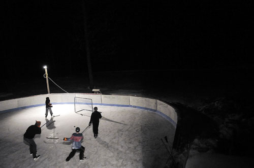 PLAYING FOR FUN: Kids play pickup hockey at Vaughn Smith’s lighted rink at his home in West Gardiner.