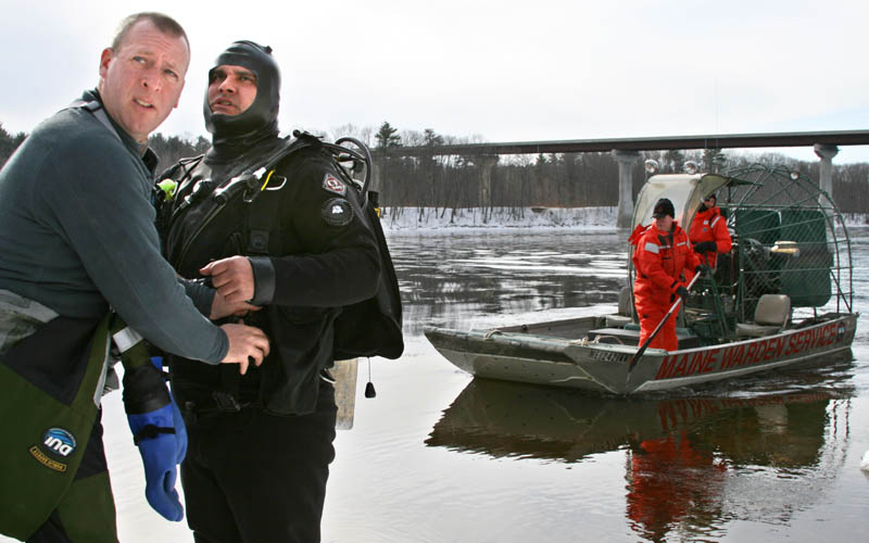 Dive Warden Robert Johansen, left, helps fellow diver Mike Pierre prepare today for a search of the Kennebec River below the Carter Memorial Bridge. Dive teams from the warden service and state police are searching two areas in Waterville for missing toddler Ayla Reynolds.