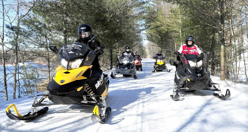 Scott Newton, left, of North Country Rivers in Bingham, leads snowmobilers down Interconnected Trail System ITS 87 recently. Low snow amounts are beginning to pick up, and the company is counting on improving snow conditions for the rest of February and March snowmobile rental business.