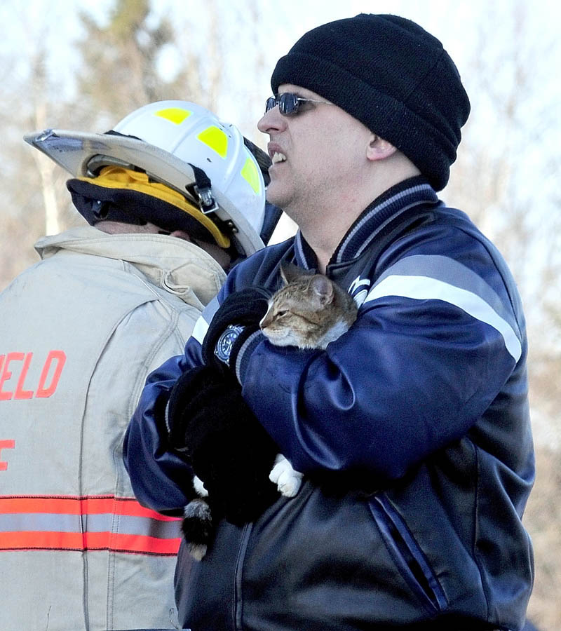 SAFE: Deril Stubenrod holds his rescued cat Mittens that firefighters pulled out of the burning home owned by his father Charles Stubenrod on Gogan Road in Benton on Thursday.