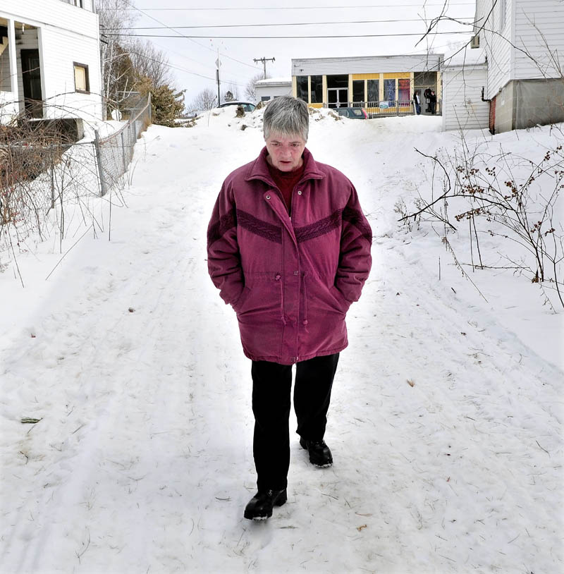 CLUES: Janice Gitschier walks the trail on Wednesday from Main Street in Bingham to Baker Street where she and Ernest Sayers were living. The trail had blood spots on it a short distance from where Sayers' body was found Sunday.