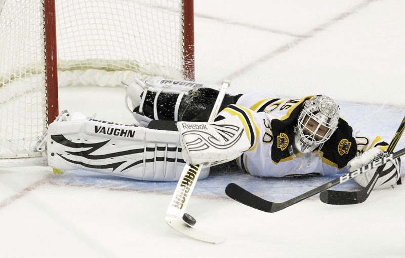 GET OUT OF HERE: Boston Bruins goalie Tim Thomas (30) swats away a shot during the first period against the Washington Capitals on Sunday in Washington. Thomas made 35 saves and the Bruins won 4-1.