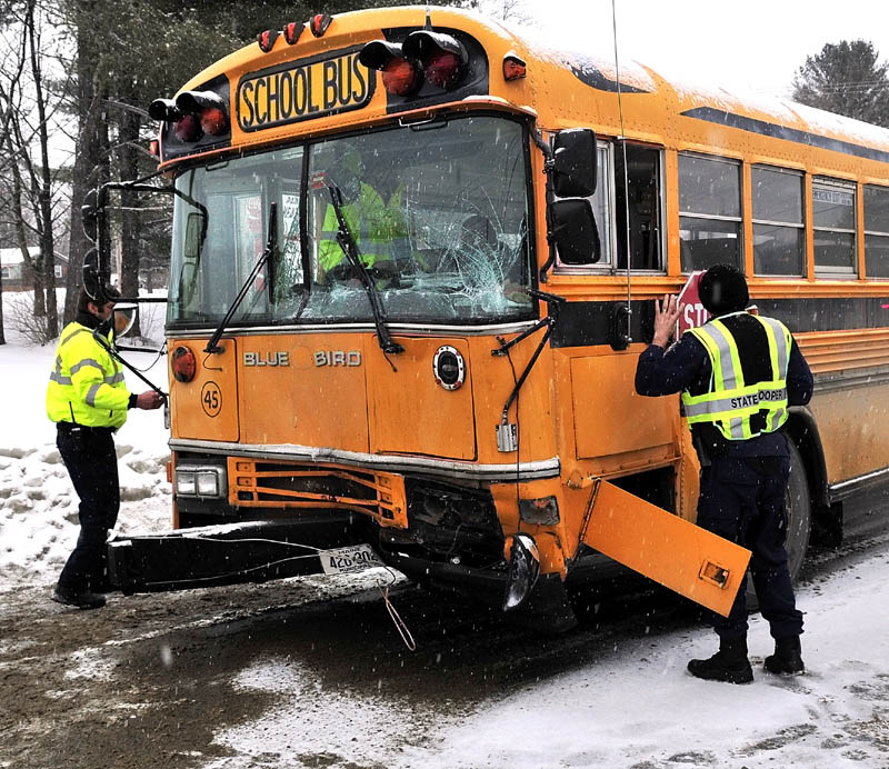 HEAD ON: Maine State Police Trooper Derek Record gestures to a bus driver while conducting an inspection after the bus and a tractor-trailer collided in Farmington on Tuesday, injuring four students.