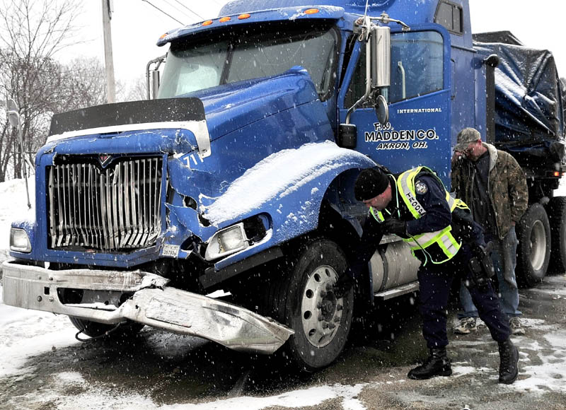 COLLISION: Maine State Police Trooper Bernard Brunette inspects a loaded tractor-trailer that was involved in a collision with a school bus in Farmington on Tuesday. The driver of the truck, Michael Matheny, is speaking on a cellphone.