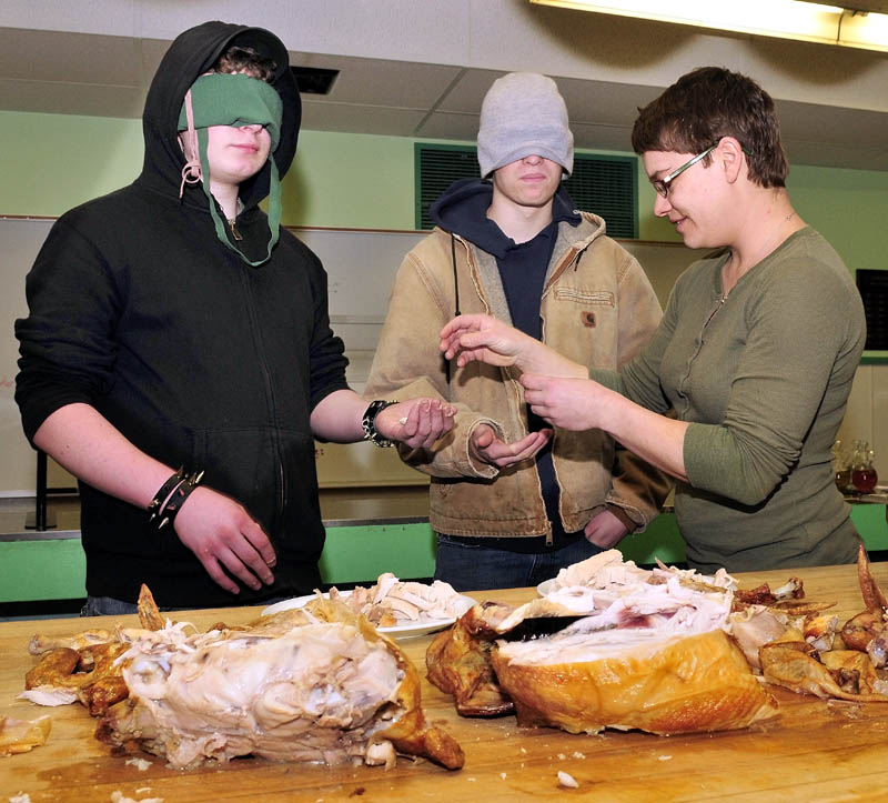 TASTE TESTERS: Maine Academy of Natural Sciences students Zach Brady, left, and David Hill are blindfolded and given a sample of cooked chicken meat by Rose Hoad of Emma's Family Farm. One sample came from the farm and the other from a supermarket. Hoad earlier cut up one of the farm-raised birds and discussed the properties of the chickens compared to commercial-grade birds both in taste and composition.