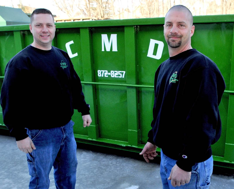 Mickey Wing, left, and his brother, Charlie Wing, stand beside one of the many Dumpsters used by Central Maine Disposal in Fairfield. The business has received the 2011 Business of the Year award from the Mid- Maine Chamber of Commerce.