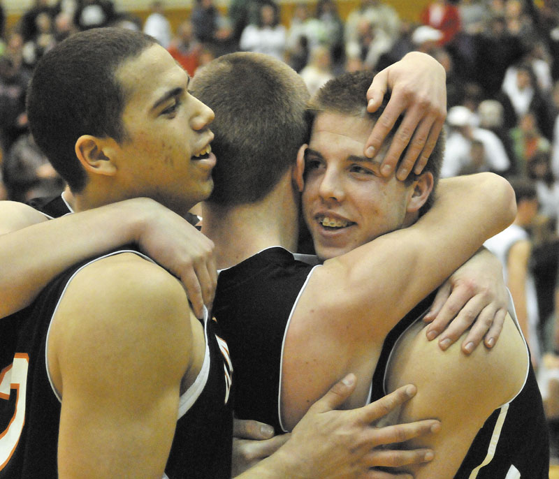 JOB WELL DONE: Gardiner Area High School’s Matt Hall, right, hugs a teammate while Alonzo Connor, left, also celebrates after the Tigers beat Mt. Desert Island 70-58 in the Eastern Maine Class B final Saturday at the Bangor Auditorium.