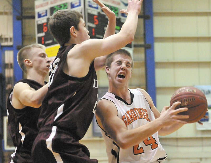 Gardiner's Matt Hall, right, drives the lane as Nokomis Andrew Cartright, 23, center, and Drew Wing, 33, left, try to defend in the first half of the Eastern Class B quarterfinals game at the Bangor Auditorium Friday. Gardiner won 56-47 in over time.