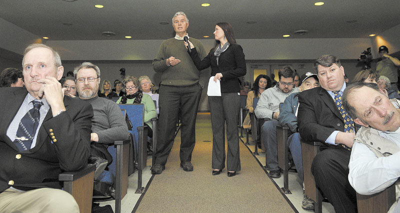 Adrienne Bennett, right, press secretary for Gov. LePage, holds the microphone for Bob Farley, of Norridgewock, as he asks the governor a question regarding religion in school during a town hall meeting at Madison Junior High School Thursday night.