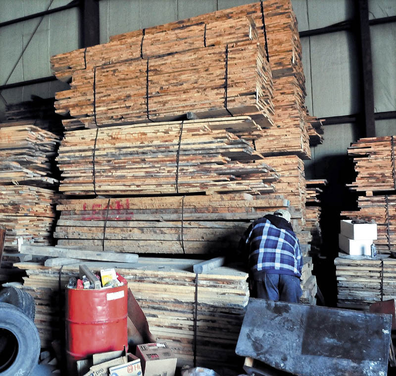 LUMBER TAKEN: An employee at Premium Log Yards Inc. in North Anson looks over stock of bundled curly maple boards stored in a building on Thursday.
