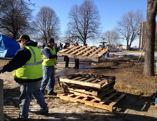 Portland Public Services employees stack pallets for removal by a forklift today in Lincoln Park. Occupy Maine protesters had used the pallets as platforms for their tents.