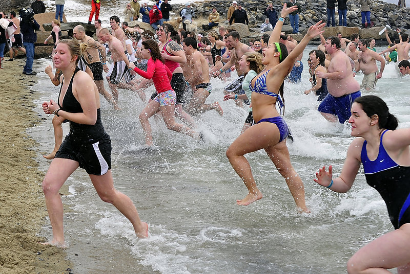 QUICK IN AND OUT: Participants rush from the cold water only seconds after they took the plunge in the Camp Sunshine Freezin' for a Reason Polar Dip at East End Beach.