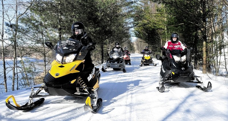 REVVED UP: Scott Newton, left, of North Country Rivers in Bingham, leads a group of snowmobilers down the Interconnected Trail System 87 trail recently. The snowmobile rental business is counting on improving snow conditions for the rest of February and March to make up for a poor start to the season because of low snowfall totals.