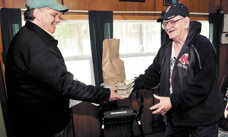 In this 2014 file photo, Clifford Groder Sr., right, of Skowhegan, accepts delivery of three days of food from Ryan Poirier, volunteer driver for Spectrum Generations’ Meals on Wheels program.