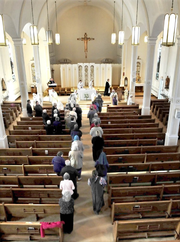 FINAL DAYS: The Rev. Joseph Daniels, left, and the Rev. Jacques Dolbec conduct communion services with parishioners at St. Francis de Sales Church in Waterville on Thursday.