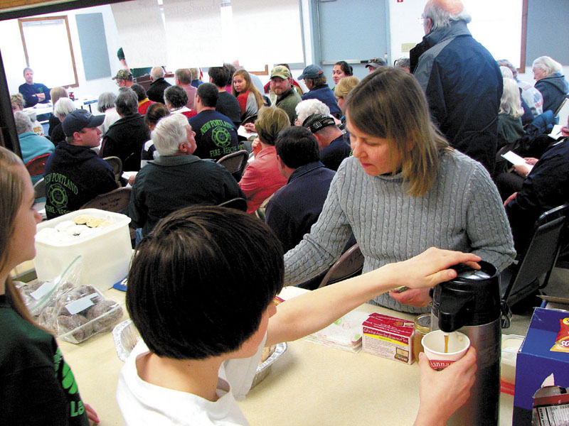 RAISING FUNDS: Taylor Bartlett, 13, left, and Tyler Reichert, 14, both of New Portland, serve resident Nora West during the New Portland Town Meeting on Saturday. The two were selling food in order to raise money for their eighth grade trip to Washington, D.C.