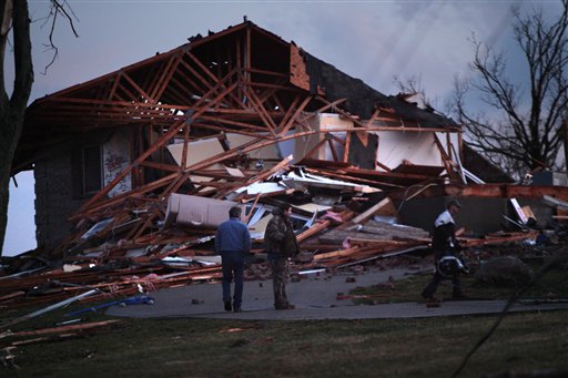 Doug Imhoff, center, stands in front of his home, in Piner, KY Friday. He had taken refuge in its basement as an apparent tornado swept through the area Friday evening. (AP Photo/The Enquirer, Carrie Cochran)