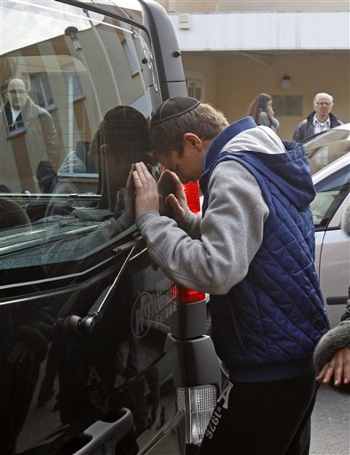A youngster cries against a hearse today, following a ceremony at the Ozar Hatorah Jewish school in Toulouse, where a gunman opened fire on Monday, killing four people.