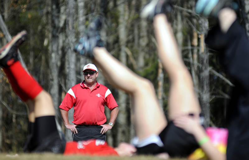 STRETCHING OUT: Cony High School softball coach Rocky Gaslin watches his team stretch Monday afternoon on the school’s practice field. Catchers and pitchers reported for the first day of practice.