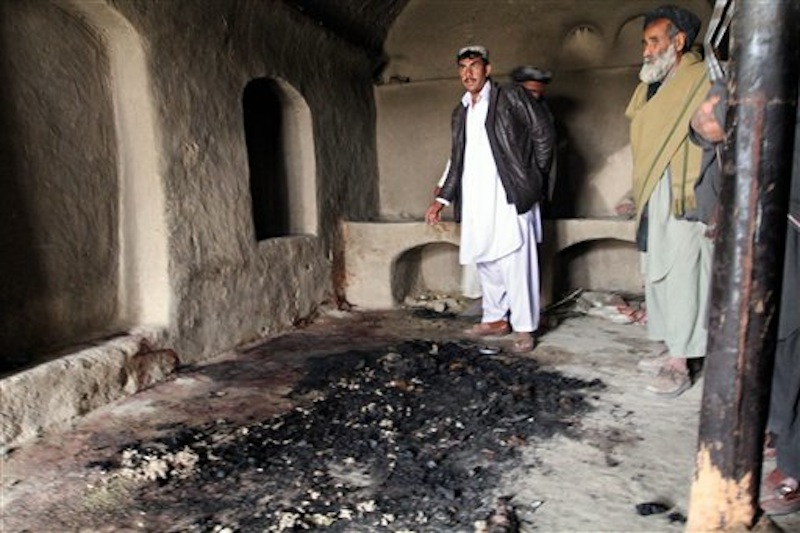 In this Sunday, March 11, 2012 photo, men stand next to blood stains and charred remains inside a home where witnesses say Afghans were slaughtered by a U.S. soldier in southern Afghanistan. (AP Photo/Allauddin Khan)