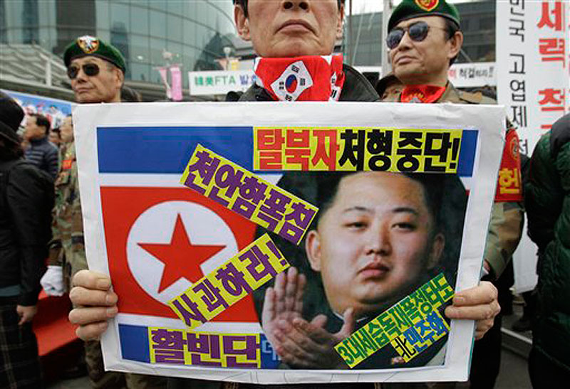 A South Korea's veteran holds a placard showing North Korea's new leader Kim Jong Un and flag during an anti-North Korea protest rally in Seoul, South Korea on Friday, March 16, 2012. North Korea announced Friday it will launch a long-range rocket mounted with a satellite in honor of late President Kim Il Sung's April birthday. (AP Photo/Lee Jin-man)