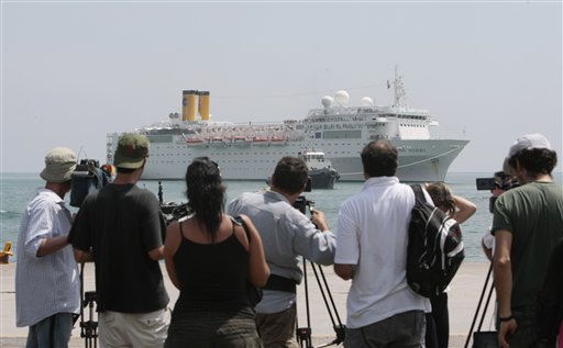 Members of the media and onlookers watch the Costa Allegra cruise ship as it is towed in Victoria harbor, Seychelles Island, today.